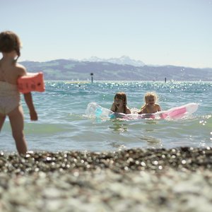 Kinder mit Schwimmflügel und Luftmatratze am Bodensee